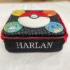 Close-up of Harlan embroidered on a black Pokémon lunch bag with a red zip