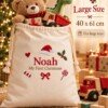 Cream organic cotton Christmas sack embroidered with Noah and My First Christmas, filled with toys beside a Christmas tree