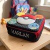 Pokémon lunch bag with Harlan embroidered on the front, displayed on a school desk