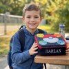 Child holding a Pokémon lunch bag embroidered with Harlan outdoors